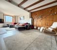 Living room with wooden wall, carpet, couch, armchair, TV, window, skis on wall