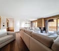 Modern living room with wooden flooring, white walls, glass windows with balcony, chandeliers, sofas, TV, dining table, chairs.
