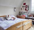 bedroom with a bed, wooden cabinet, shelf with personal items, two red laundry baskets, white clothing rack