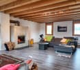 Modern living room with a fireplace, wooden ceiling, carpeted floor, sofa, coffee table, rug, decorative pillows, and potted plants