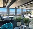office room with large windows, modern desk setups, comfortable seating options, indoor plants, carpeted floor, natural light