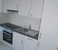 modern fitted kitchen with white cabinets, marble countertop, stainless steel sink, electric oven and hob, washing machine