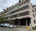 office building, grey facade, brown windows, several floors, parking lot, entrance