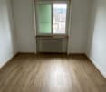 empty room, wooden floor, white walls, window with green shutters, radiator