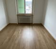 empty room, wooden floor, white walls, window with green shutters, radiator