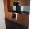 modern kitchen with stainless steel appliances, wooden cabinets, black countertops