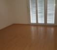 Empty room with wooden flooring, glass doors, and white walls
