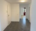 Empty hallway, gray tiles, white walls, white door, white ceiling, single light fixture