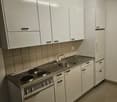 modern kitchen, white cabinets, gas stove, stainless steel sink, refrigerator, dishwasher, washing machine, tiled backsplash