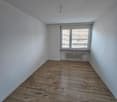 an empty room with white walls, wooden floor, and a window with blinds