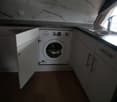 modern kitchen with marble tiles, white cabinets, dishwasher, washing machine, sink