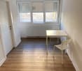 empty room with wooden floor, white walls, white table, white chairs, radiator, windows with shutters