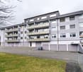 5 story apartment building, white walls, balconies, garage