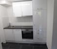 Modern kitchen with white cabinetry, tiled flooring, a sink with a faucet, a built-in oven, and a dishwasher.