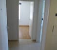 Empty hallway, white tiles, wooden floor in one room, white doors