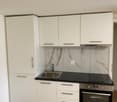 modern kitchen with white cabinets, black countertop, stainless steel sink, oven, dishwasher, washing machine