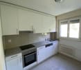 modern kitchen with white cabinets, tiled floor, stainless steel appliances, window with blinds, radiator