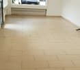 Empty room with white walls, beige tiles, large window, car visible outside