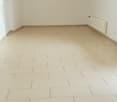 Empty room with white walls, white ceiling, white tiled floor, two windows, white radiator