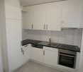 modern kitchen with white cabinets, black countertops, stainless steel sink, dishwasher, oven, and refrigerator