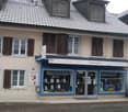 Two-story building with a tiled roof, multiple windows, and a shopfront with a sign reading 'Servicestelle'.