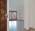 Large room with wooden paneled doors, tile flooring, and a sliding glass door leading to a balcony or terrace with a view of the mountains.