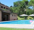 Brick building, swimming pool, outdoor dining area, umbrellas, trees, green lawn