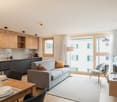 open plan living space with kitchen, dining area, sofa, carpet, TV, wooden flooring, large windows