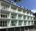 3-story modern apartment building with glass balconies, white exterior, and large windows