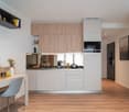 Modern kitchen with light wood cabinets, white appliances including a dishwasher, and a small dining area with a table and chair.