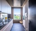 Modern kitchen with gray cabinets, stainless steel sink, and large window with a view of the city skyline
