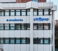 A modern, multi-story office building with large windows and signage for 'Macademia' and 'Citypop' companies. The building has a clean, contemporary architectural style with a mix of glass and white panels.