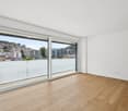 Empty room, wooden floor, white walls, large glass sliding doors, balcony with view, power outlets