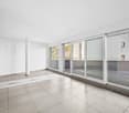 Empty room with white walls, tile floor, large windows and balcony