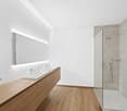 Bathroom with 2 sinks, walk-in shower, wall-mounted mirror, wooden floors, power outlet, wooden cabinets, tiled walls