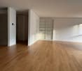 Empty room with wooden floors, white walls, built-in shelves, and open closet
