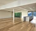 modern open kitchen with a large counter, sliding glass walls, hardwood floors, open to a balcony