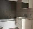 modern bathroom with white bathtub, sink, modern toilet and cabinet, mirror and lighting