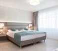 double bed, night tables, side lamps, electrical outlets, windows, curtains