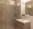 modern bathroom with walk-in shower, sink, and vanity unit, glass walls and floor
