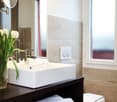 Modern bathroom with white walls, vessel sink, dark wood vanity, and towels stored in the vanity cabinet