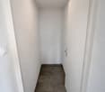 Empty hallway, white walls, beige tile flooring, ceiling light