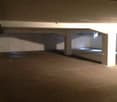Large empty parking space with exposed ceiling beams and concrete floor.