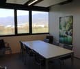 empty meeting room with large windows, long table, black chairs, painting on the wall