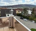 Balcony with glass railing, street view, houses, cars, trees, mountains