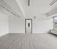 empty room with white walls, gray floor, white ceiling, clock, window with view