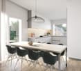 The image shows a modern, open-concept kitchen and dining area. The kitchen features white cabinets, a gray countertop, and a pendant light fixture. The dining table is made of light-colored wood and is surrounded by black chairs. Large windows provide na