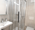 Modern bathroom with a glass shower enclosure, white sink, white toilet, and tiled floor.