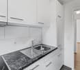 modern kitchen with white cabinets, marble countertop, stainless steel sink, faucet, electrical outlet, and power outlet