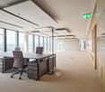 Large open office space with floor-to-ceiling windows, providing a panoramic view of the city. The office features modern furniture, including desks and chairs, as well as a clean and minimalist design. The space appears to be a professional work environm